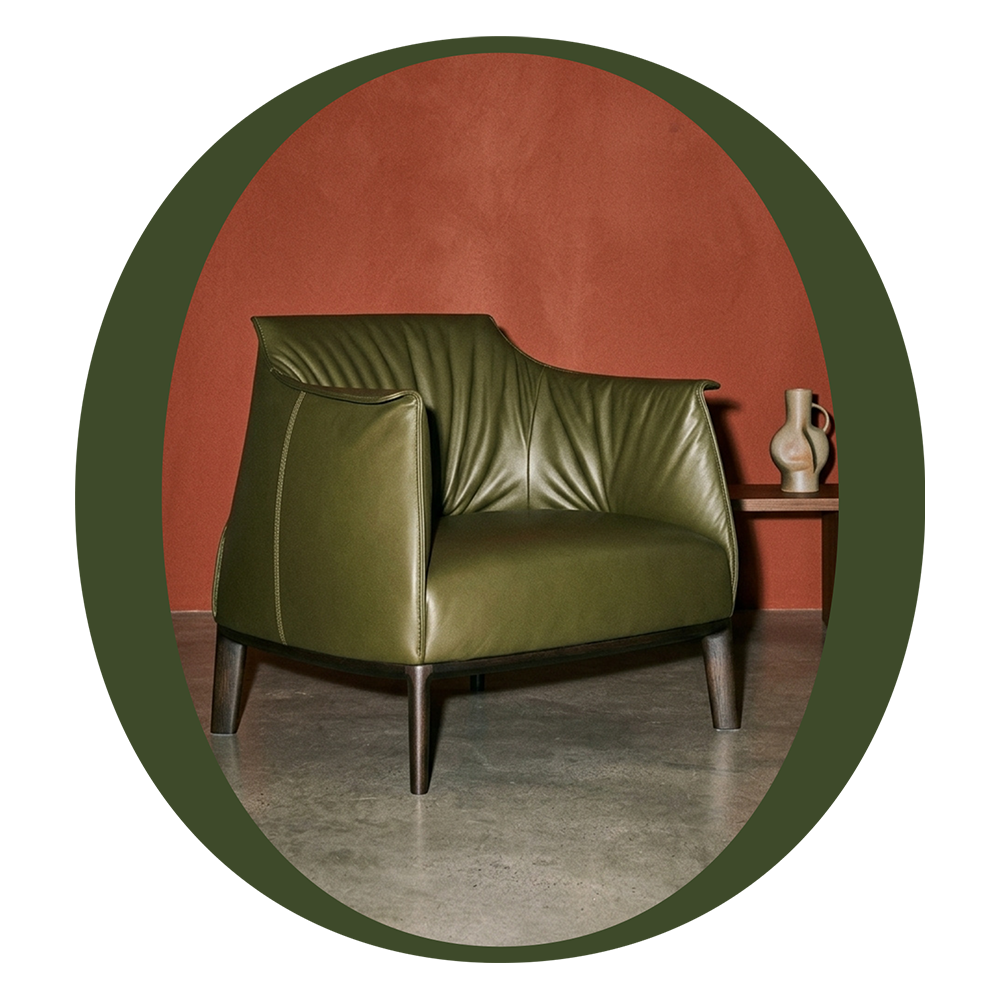 Olive-green leather armchair against a warm terracotta wall with a small side table and ceramic vessel
